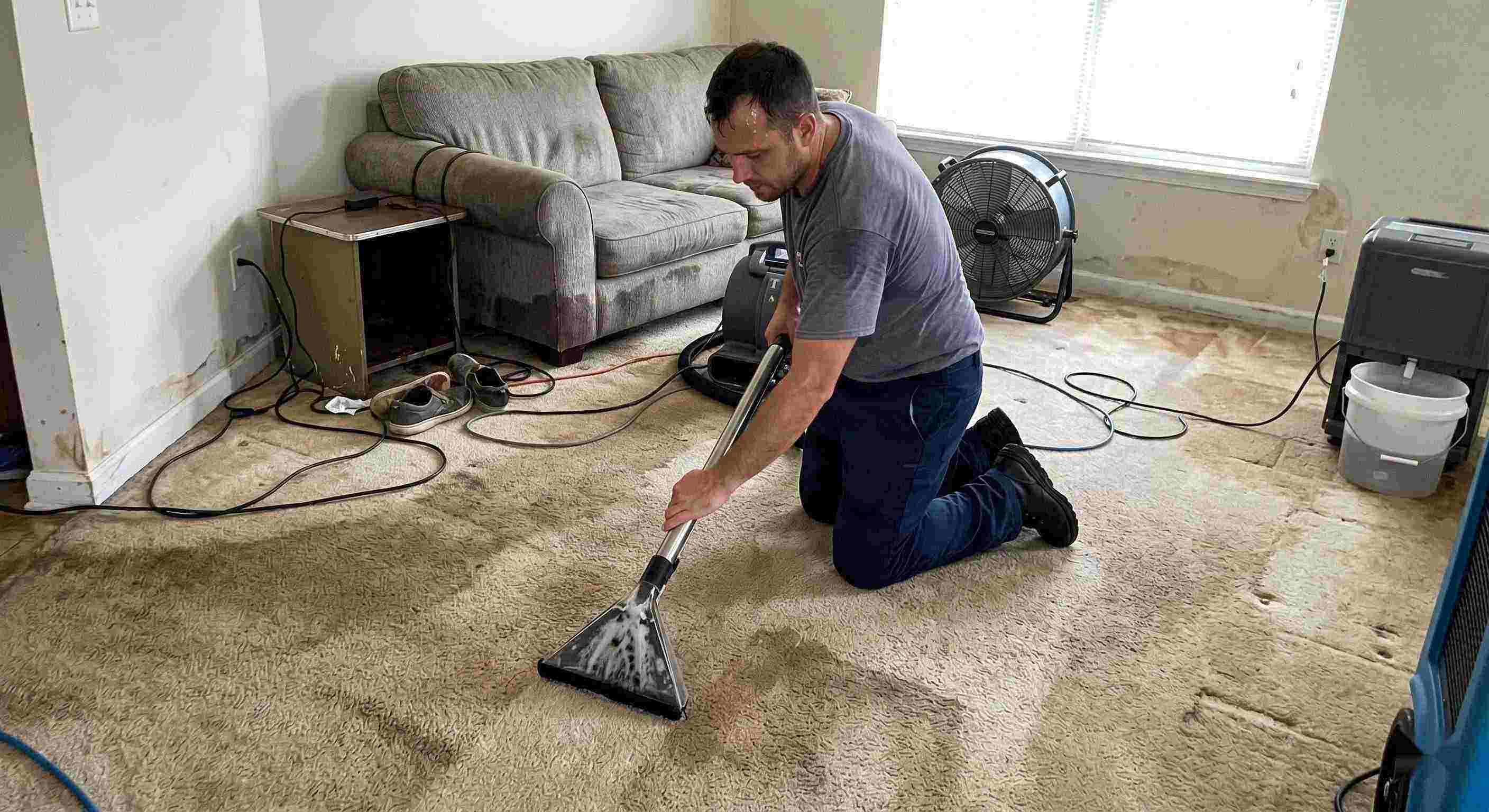 Technician performing carpet water extraction in a residential home using professional equipment after water damage in St. Petersburg