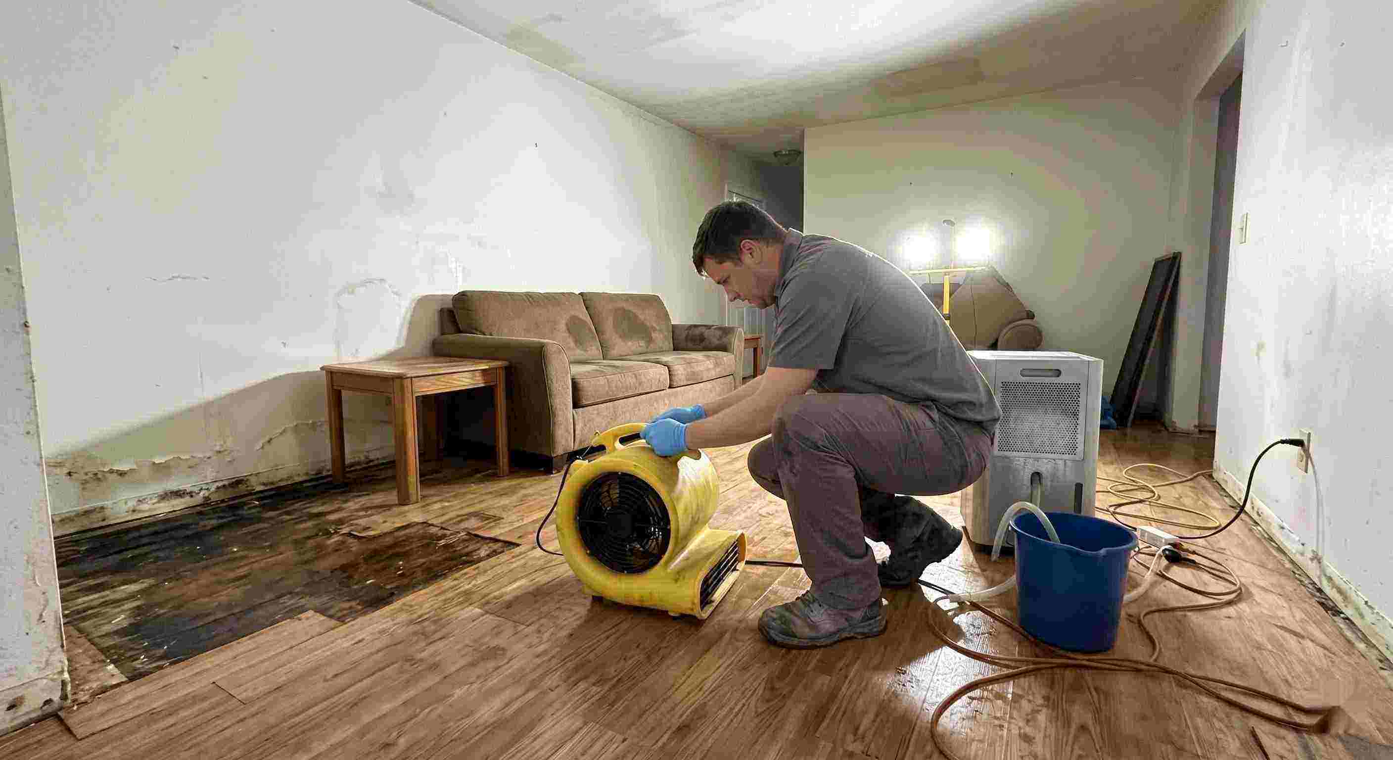 Local water damage restoration technician drying wet floors with equipment during cleanup process in Spring Hill